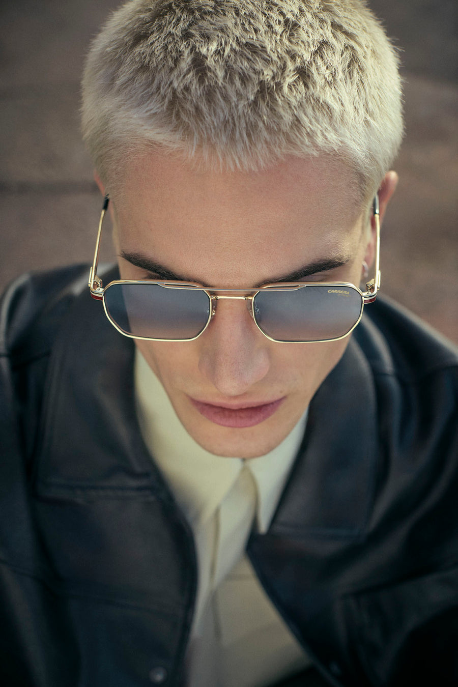 Official Carrera portrait with gold-framed sunglasses and a leather jacket